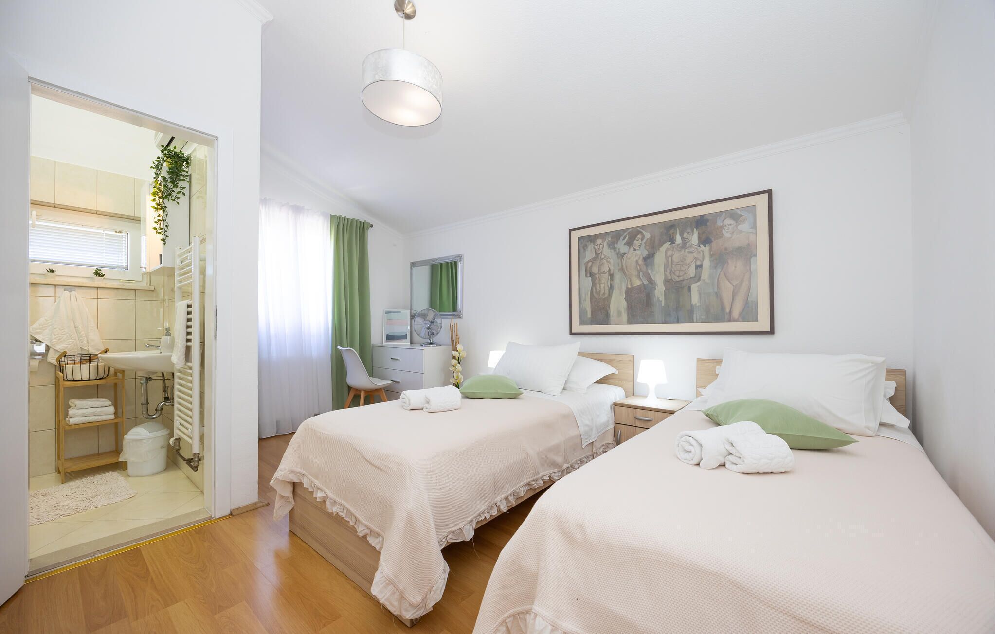 Une chambre d’hôtel avec deux lits, une salle de bain, un bureau et un tableau au mur.