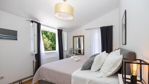 A bedroom with a bed, a bedside table, a mirror, and a window with curtains. - Amazing home in Lucane (Lucane)
