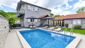A rectangular swimming pool with a tiled deck, surrounded by lounge chairs and umbrellas. - Amazing home in Lucane (Lucane)
