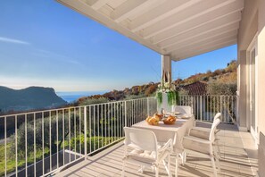 Ein Balkon mit Esstisch, mit Blick auf eine reizvolle Landschaft aus Bergen und Bäumen.
