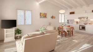 A modern living room with a sofa, TV, and dining area with a table and chairs. - White Apartment with Terrace and Lake View (Costermano)