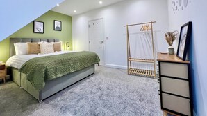 Ein Schlafzimmer mit Bett, Kleiderschrank, Kleiderstange und Tür.