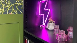 A shelf with a neon lightning bolt sign, a potted plant, and several glass containers. - 3BR | Contractors | Parking, Garden (Saffron Walden)