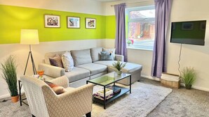 A living room with a sofa, armchair, coffee table, and a TV. - 3BR | Contractors | Parking, Garden (Saffron Walden)