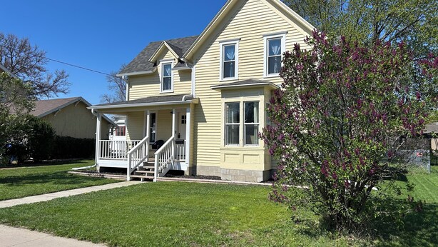 A two-story house with a porch and a front yard.