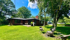 Een gelijkvloers bakstenen huis met een grote tuin, terras en garage.