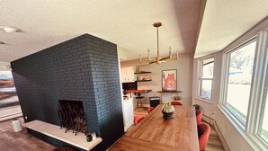 Een moderne keuken met een metselwerk schoorsteen, een houten eettafel en rode stoelen.
