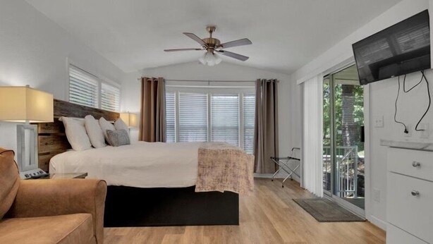 Ein Schlafzimmer mit einem Bett, einem Deckenventilator, einem Fernseher und Blick ins Freie.