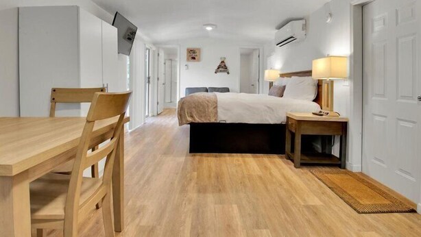 Et hotelværelse med en seng, et sengebord, en lampe og en træstol.
