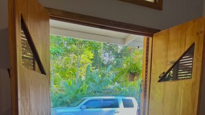 Un coin repas avec une table, deux chaises, une bouteille de vin et un verre. Une voiture est garée devant la fenêtre.