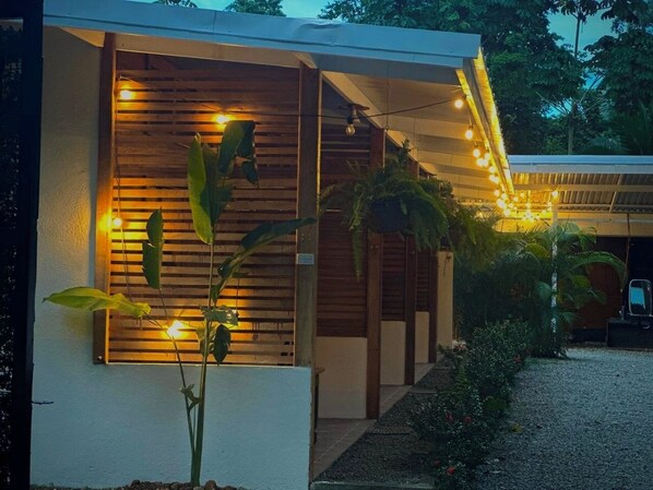 A modern building with a covered outdoor area, wooden slats, and string lights.
