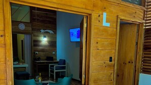 Une cabane en bois avec une grande fenêtre, un téléviseur et une table recouverte de papiers.