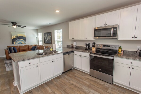 A modern kitchen with white cabinets, stainless steel appliances, and a granite countertop.