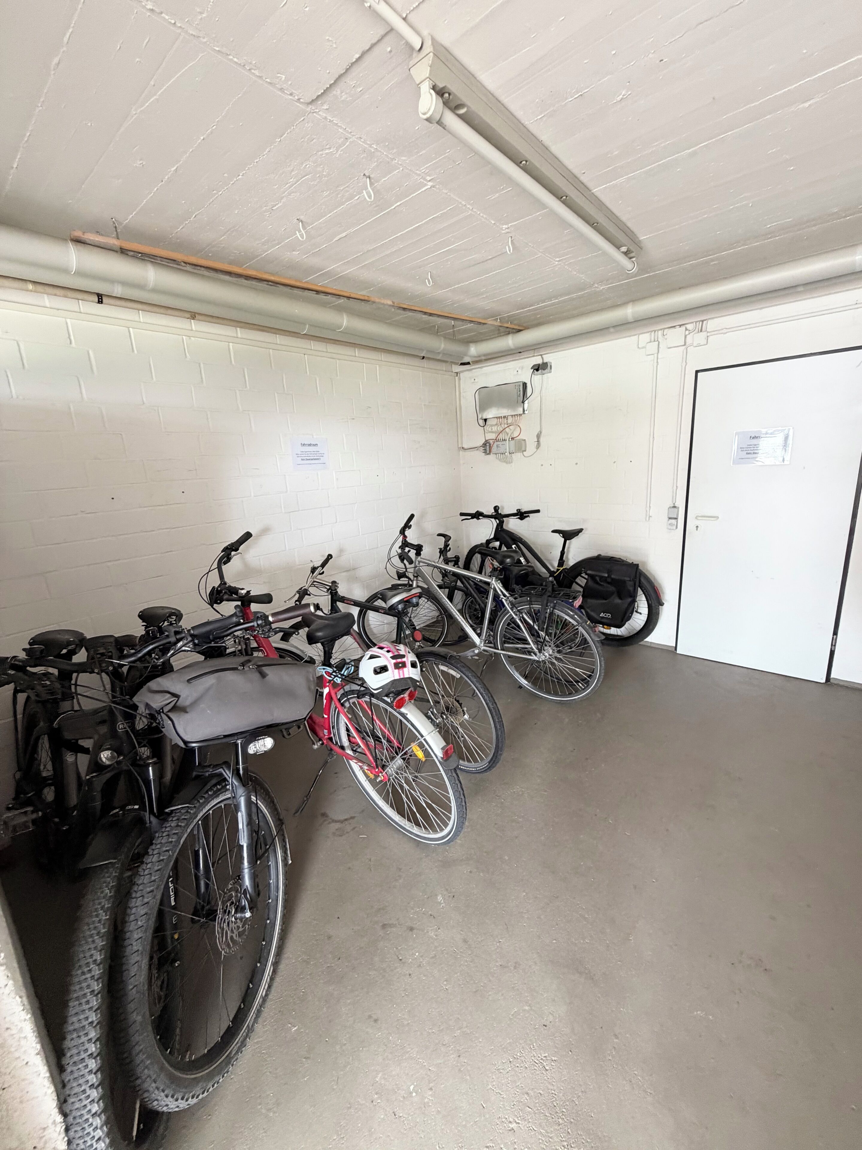 Een parkeergarage met fietsen en een witte deur.