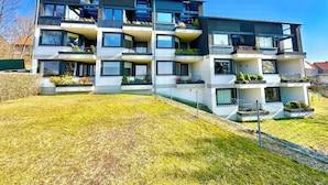 Ein modernes Mehrfamilienhaus mit Balkonen, großen Fenstern und einem gepflegten Rasen.