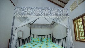 A bed with a canopy, a patterned bedspread, and a window with bars. - Thuru Sewana Villa (Unawatuna)