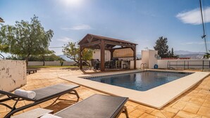 A pool area with lounge chairs, a covered seating area, and a view of the mountains. - 3 bedroom stunning home in Coin (Coin)