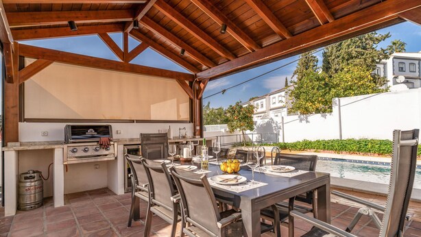 An outdoor patio with a grill, dining table, chairs, and a pool. - 3 bedroom stunning home in Coin (Coin)