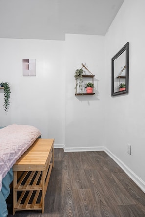 Cozy retreat with a single bed, wooden bench, and potted plants.