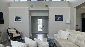 A modern living room with a white sofa, a wicker chair, and a blue patterned rug. - Sea Level BSL 3BR 3BA Waterfront (Shoreline Park)