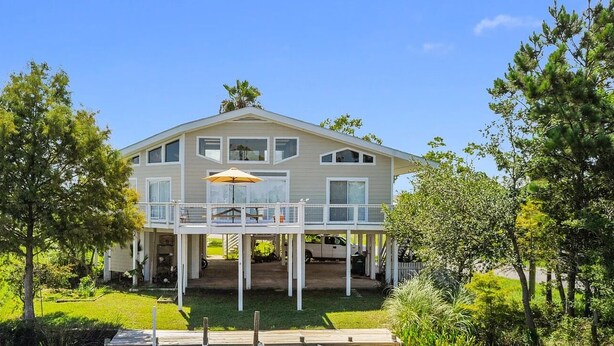 A two-story house with a covered porch and a large umbrella. - Sea Level BSL 3BR 3BA Waterfront (Shoreline Park)