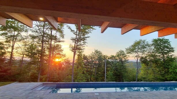 A swimming pool with a view of trees and a sunset. - The Retreat - Mountain chalet - piscine & spa (Sainte-Béatrix)