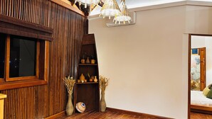 Habitación con pared de listones de madera, una ventana, estante con objetos decorativos y una cama con vista a un muro de piedra.