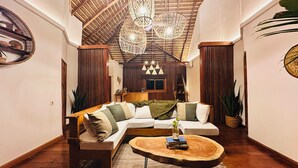 Un salón acogedor con techo de madera, un sofá modular y una mesa de centro redonda de madera.