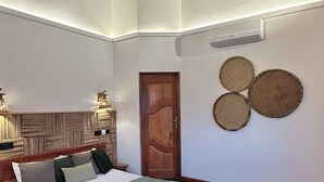 Un dormitorio con una cama de madera, un ventilador de techo, una puerta y decoración tejida en la pared.
