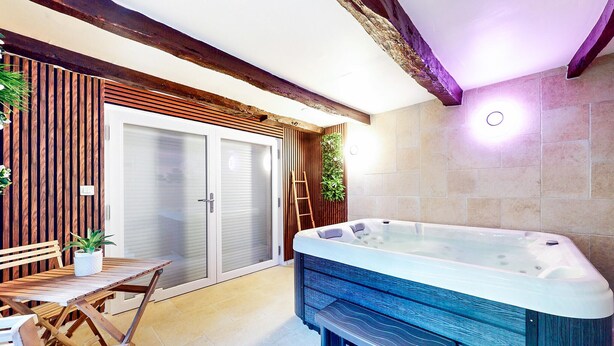 Zona de spa con jacuzzi, muebles de madera y puerta corredera de vidrio.