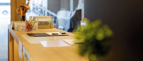 A reception desk with a laptop, a clipboard, and a plant.