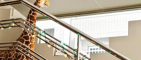 A giraffe statue near a staircase with metal railings and string lights.