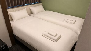 Habitación de hotel con dos camas, cada una con ropa blanca y toallas dobladas.