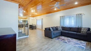 Una sala de estar moderna con techo de madera, sofá de color oscuro y alfombra estampada.