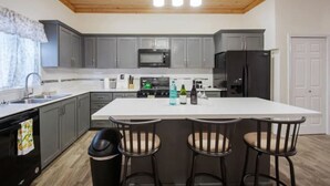 Una cocina moderna con armarios grises, una isla blanca y un refrigerador negro.