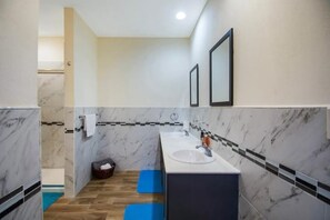 A modern bathroom with marble walls, two sinks, and a wooden floor. - Cozy 2-bedroom townhome in lovely gated community in Nassau with WiFi and AC. (Nassau)