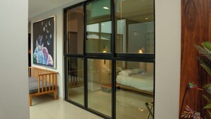 A modern room with a large glass door leading to a bedroom. A wooden chair and a painting of celestial bodies are visible. - Casa Mosso  (Oaxaca)
