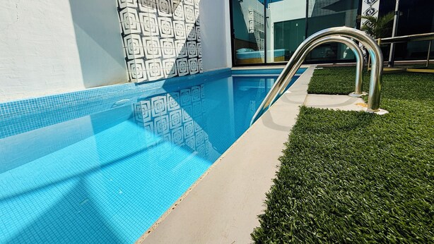 A swimming pool with a geometric tile pattern, a metal handrail, and a grassy area beside it. - Casa Mosso  (Oaxaca)