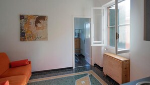 A hallway with a painting, a wooden bench, and a door leading to another room. - Tuibeds (Arenzano)
