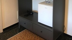 A compact, dark-colored wardrobe with a mirror, a hanging rack, and a small shelf with bottles. - Tuibeds (Arenzano)