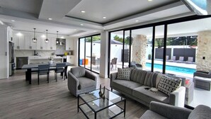 A modern interior with a dining area, kitchen, and a view of a swimming pool. - Arenal Harmony Villa - Private heated pool! (La Fortuna)