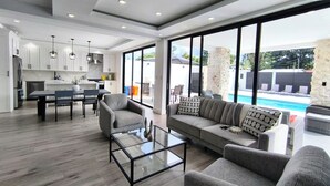 A modern living space with a dining area, sofa, and a view of a swimming pool. - Arenal Harmony Villa - Private heated pool! (La Fortuna)