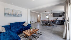 A modern living room with a blue sofa, a wooden coffee table, and a painting of sailboats.