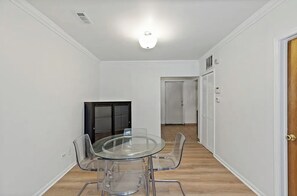 Cozy space with a round table and four chairs, a cabinet, and a door to another room.