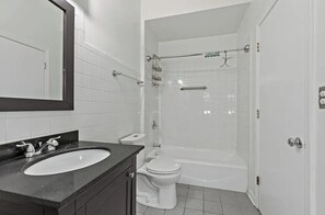 Enjoy a refreshing shower in the spacious bathroom with a separate shower area, oval-shaped sink, and large mirror.