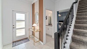 A modern interior with a staircase, a door with frosted glass panels, and a wooden accent wall.