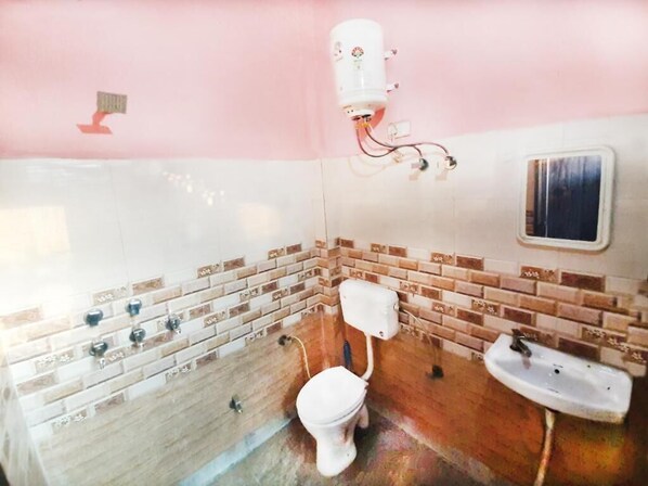 Un baño con inodoro, lavamanos y calentador de agua instalado en la pared.