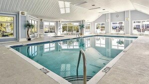 An indoor swimming pool with clear water, surrounded by windows and potted plants. - Charming 3-bedroom Golf Villa in Murrells Inlet South Carolina (Murrells Inlet)