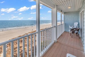 A covered porch with a view of the beach, white railings, and wicker chairs. - North Myrtle Beach, Oceanfront 7BR, Sleeps 16: Pool, Hot Tub, Game Room (North Myrtle Beach)