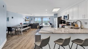 Een moderne keuken met een groot eiland, barkrukken en uitzicht naar buiten.
